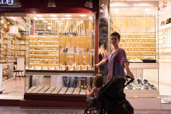 ウィンドウの宝石店の前でベビーカーでかわいい女の子と若い母親 — ストック写真