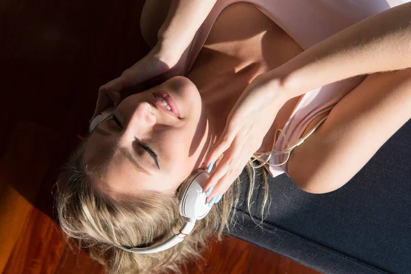 Belle femme blonde écoutant de la musique tout en se reposant sur le canapé — Photo