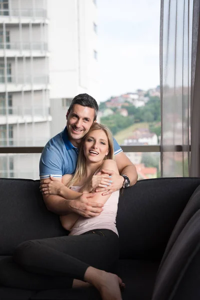 Jovem casal bonito abraçando no sofá — Fotografia de Stock