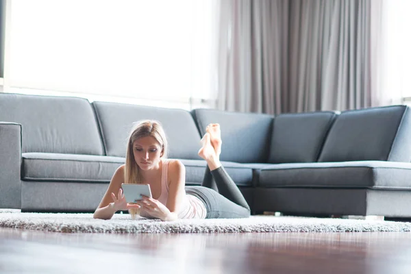 Jovem mulher usando computador tablet no chão — Fotografia de Stock