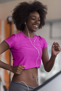 bir koşu bandı üzerinde çalışan afro Amerikalı kadın