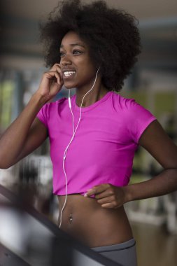 bir koşu bandı üzerinde çalışan afro Amerikalı kadın
