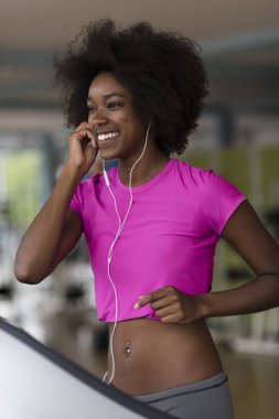bir koşu bandı üzerinde çalışan afro Amerikalı kadın