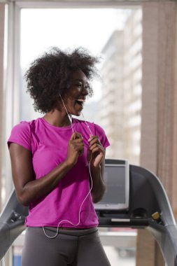 bir koşu bandı üzerinde çalışan afro Amerikalı kadın