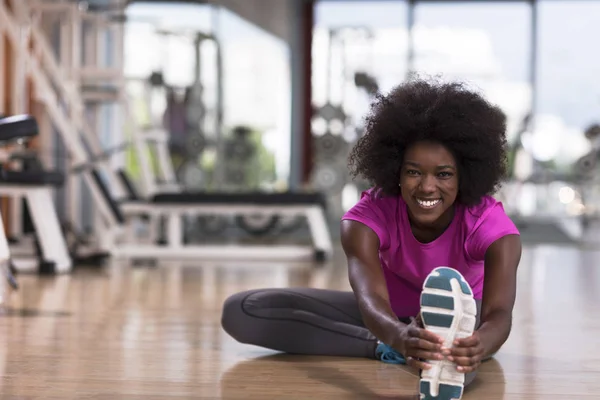 Frau im Fitnessstudio Dehnen und Aufwärmen Mann im Hintergrund arbeitet — Stockfoto