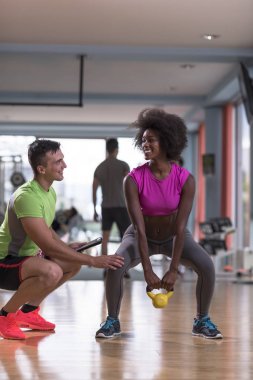 Spor salonunda kişisel antrenörle ağırlık çalışması