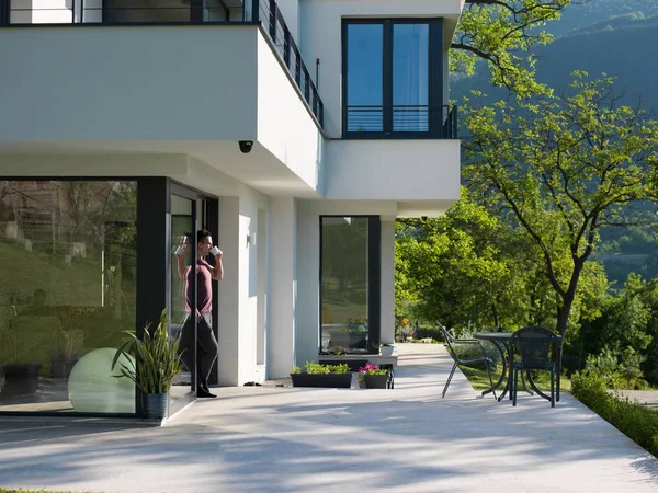 Man drinking coffee in front of her luxury home — Stock Photo, Image