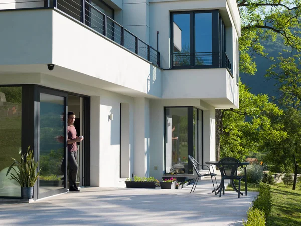 Man drinking coffee in front of her luxury home — Stock Photo, Image