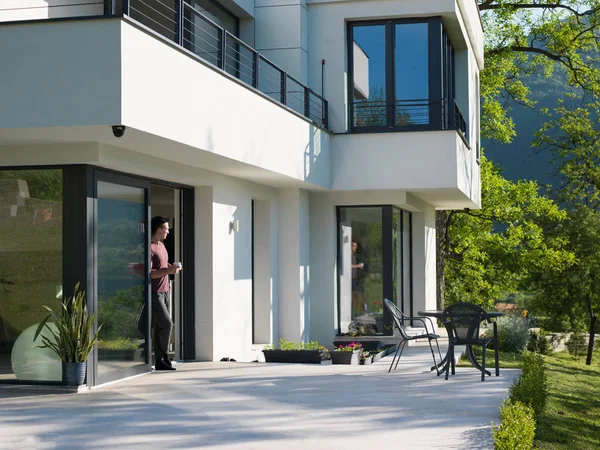 Man drinking coffee in front of her luxury home — Stock Photo, Image