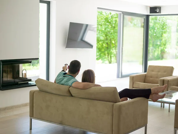 Pareja joven en el sofá viendo la televisión —  Fotos de Stock