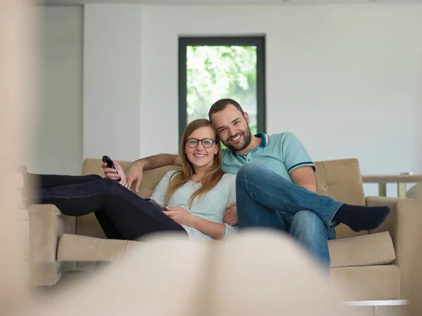 Jong (echt) paar op de bank tv-kijken — Stockfoto