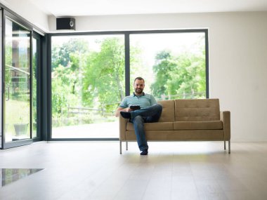 adam kanepede tablet bilgisayar kullanarak