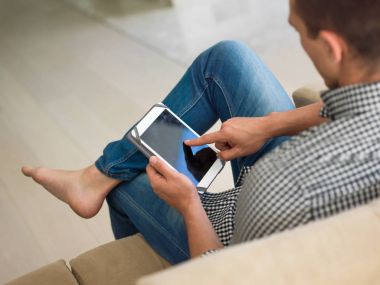 adam kanepede tablet bilgisayar kullanarak