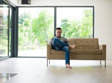 adam kanepede tablet bilgisayar kullanarak