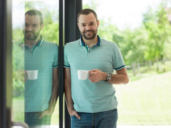Ung mann som drikker morgenkaffe ved vinduet – stockfoto