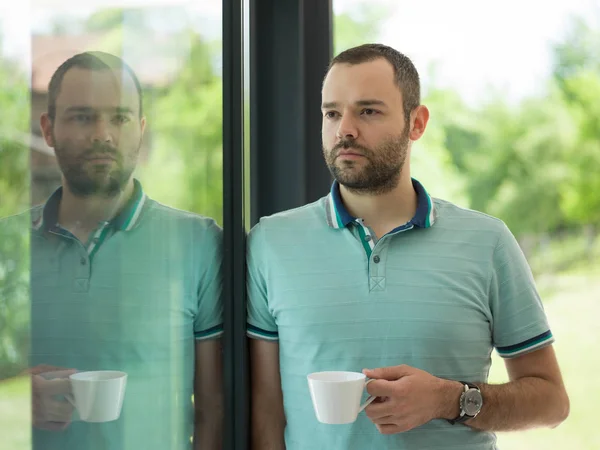 खिडकीतून सकाळी कॉफी पिण्याचे तरुण माणूस — स्टॉक फोटो, इमेज
