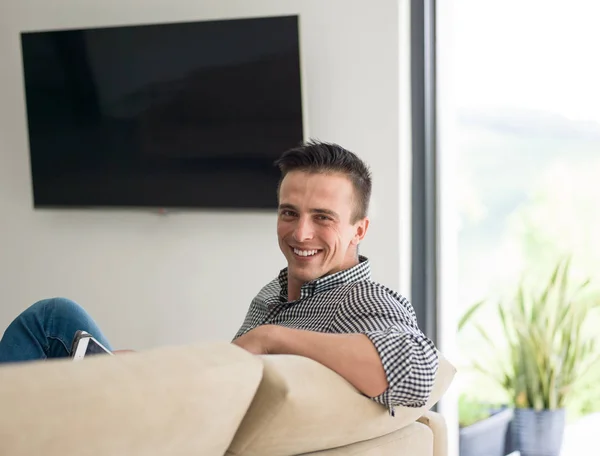 Человек на диване с помощью планшетного компьютера — стоковое фото