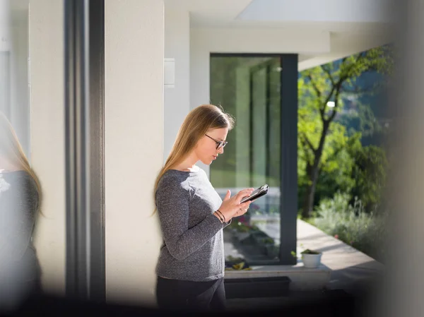 Жінка використовує планшетний комп'ютер перед розкішним будинком — стокове фото