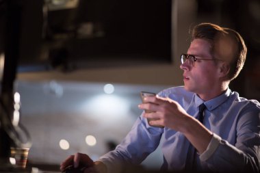 karanlık ofisinde cep telefonu kullanan adam