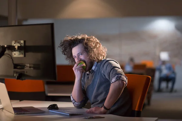 Hombre comiendo manzana en su oficina — Foto de Stock