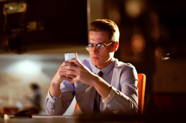 karanlık ofisinde cep telefonu kullanan adam