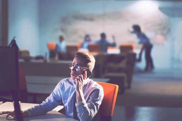 Uomo che utilizza il telefono cellulare in ufficio scuro — Foto Stock