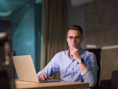 karanlık ofiste dizüstü bilgisayarda çalışan adam