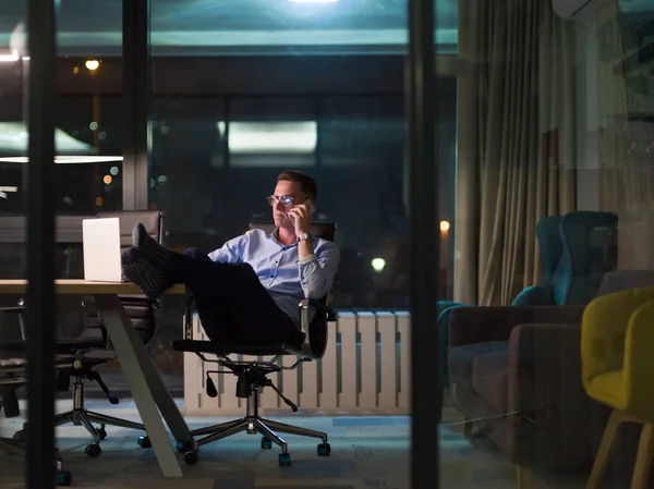 Uomo d'affari che utilizza il telefono cellulare in ufficio scuro — Foto Stock