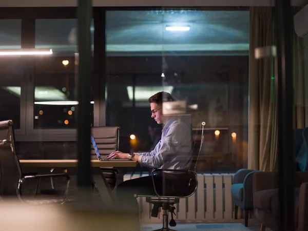 Homem trabalhando no laptop no escritório escuro — Fotografia de Stock