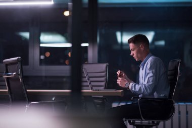 karanlık ofiste dizüstü bilgisayarda çalışan adam