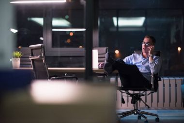 cep telefonuyla karanlık ofisinde işadamı