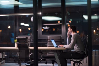 karanlık ofiste dizüstü bilgisayarda çalışan adam