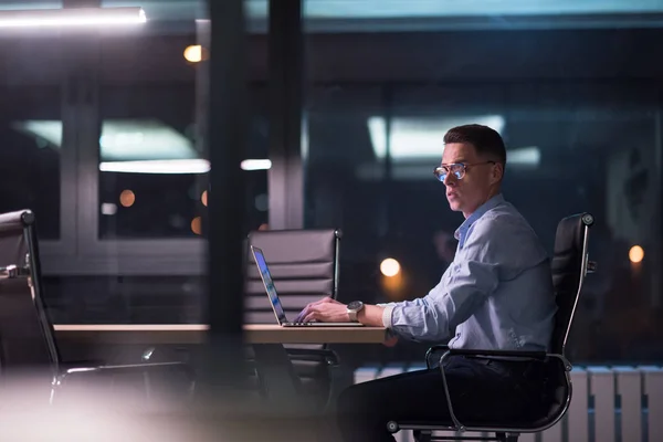 Uomo che lavora su computer portatile in ufficio scuro — Foto Stock