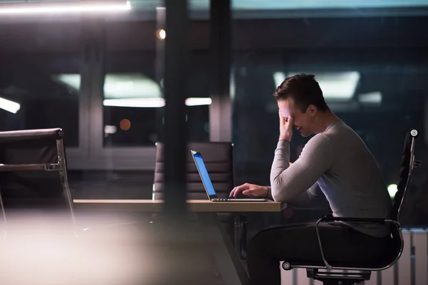 Человек работает на ноутбуке в темном офисе — стоковое фото