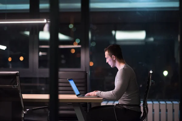 Man som arbetar på laptop i mörka office — Stockfoto