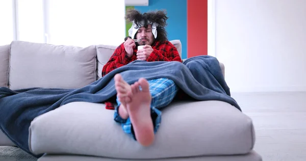 Kranker hält auf Couch eine Tasse in der Hand — Stockfoto