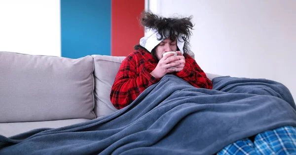 Kranker hält auf Couch eine Tasse in der Hand — Stockfoto