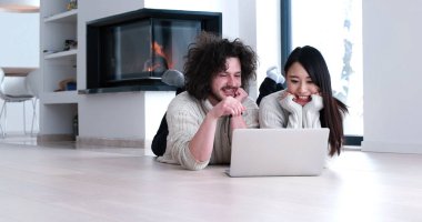 genç çok ırklı çift katta bir dizüstü bilgisayar kullanarak