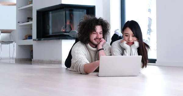 Giovane coppia multietnica utilizzando un computer portatile sul pavimento — Foto Stock