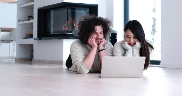 Jovem casal multiétnico usando um laptop no chão — Fotografia de Stock