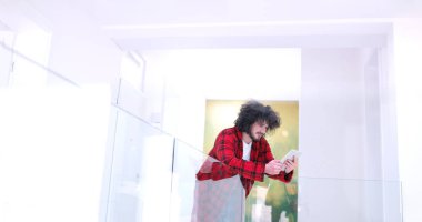 Genç adam evde tablet kullanıyor.