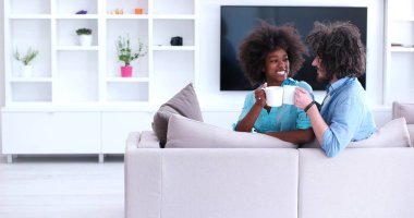 çok ırklı çift evde kanepede oturmuş kahve içme