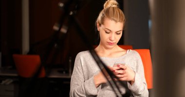 karanlık ofisinde cep telefonu kullanan kadın