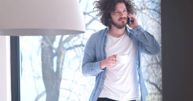 kahve içme ve evde bir cep telefonu kullanarak genç adam