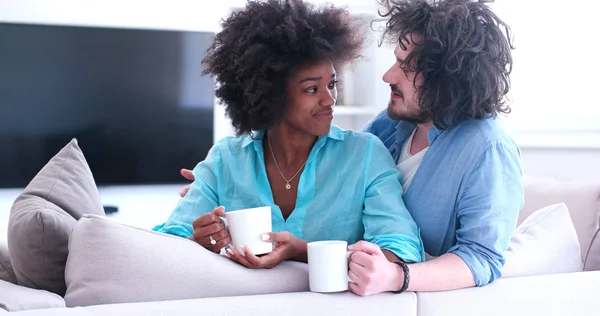 多种族的夫妇坐在家里的沙发上喝咖啡 — 图库照片