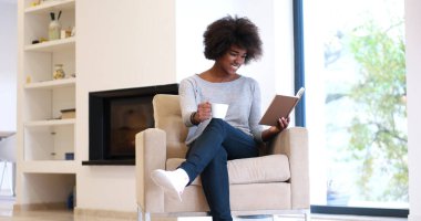 siyah kadın şömine önünde kitap okuma