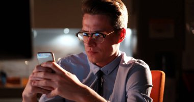 karanlık ofisinde cep telefonu kullanan adam