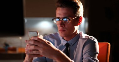 karanlık ofisinde cep telefonu kullanan adam