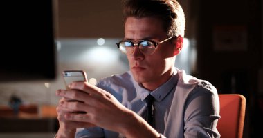 karanlık ofisinde cep telefonu kullanan adam