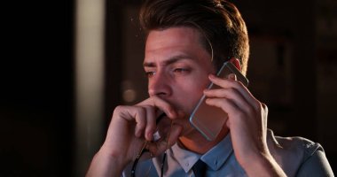 karanlık ofisinde cep telefonu kullanan adam